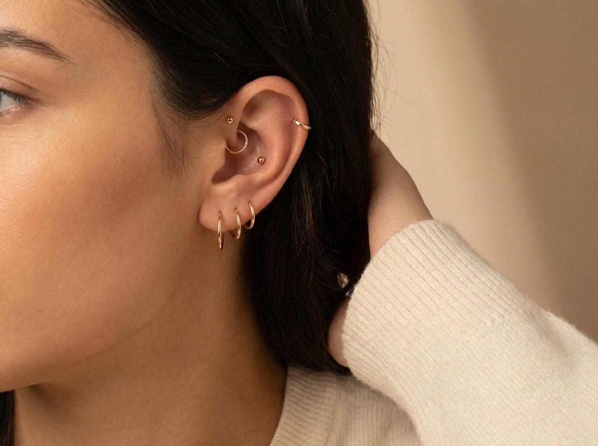 Woman's ear with multiple piercing placements — lobe, helix, tragus, daith visible