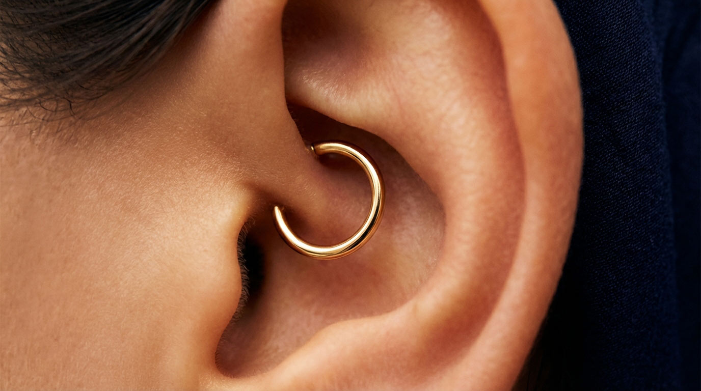 Woman's ear with daith piercing and curated inner ear 2025 — gold crescent moon clicker in daith placement paired with helix stud and stacked lobe earrings
