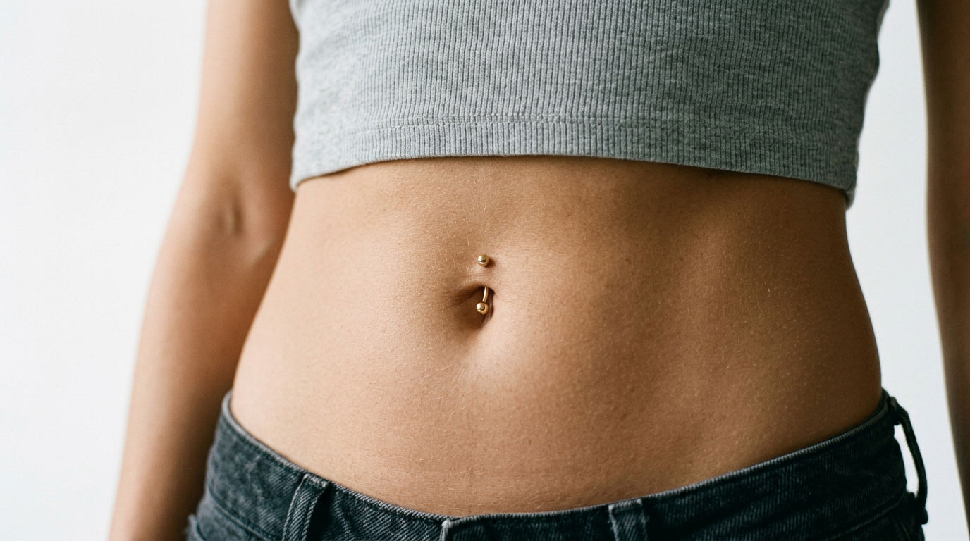 Woman's midriff with navel belly button piercing — body piercing healing times