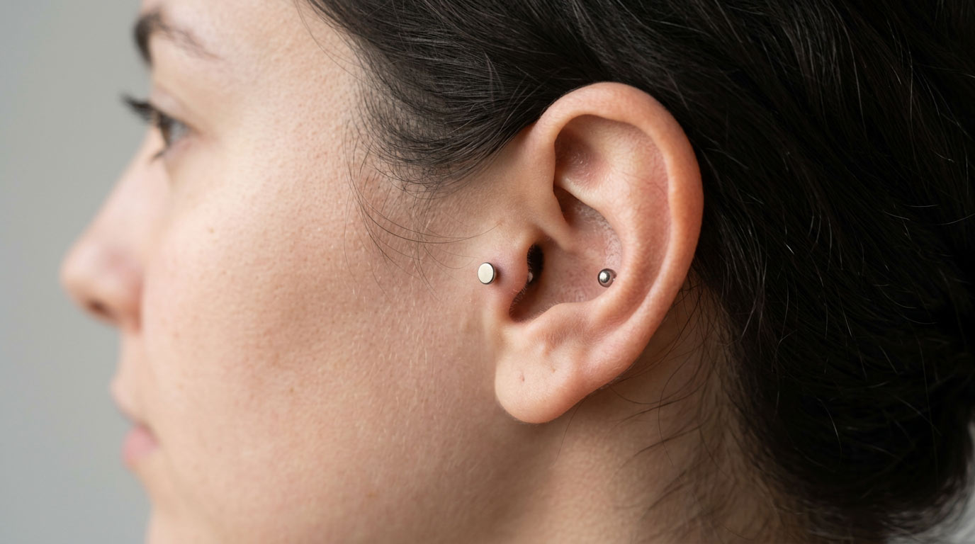 Woman's ear showing standard tragus piercing and anti-tragus piercing placements — comparison of tragus vs anti-tragus cartilage positions